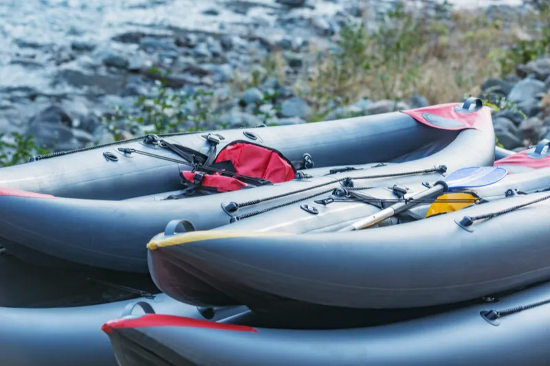 The gray inflatable kayaks waits by the lake for its owners to set off paddling